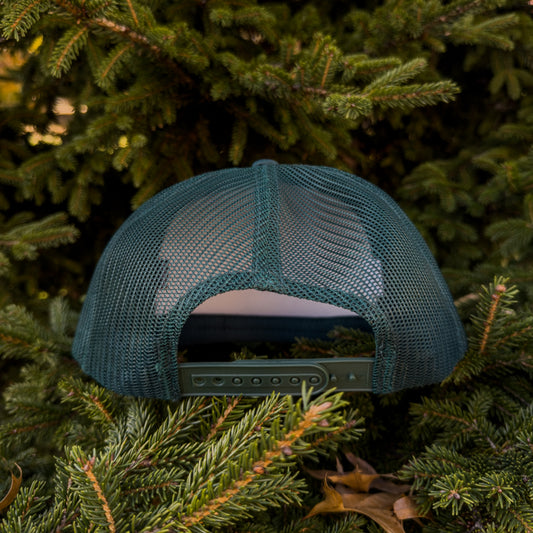 FOREST GREEN mesh cap on a bed of pine needles