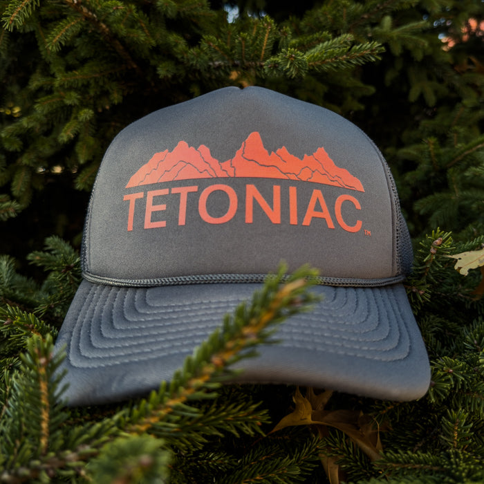 Gray cap with 'TETONIAC' logo on a background of green foliage