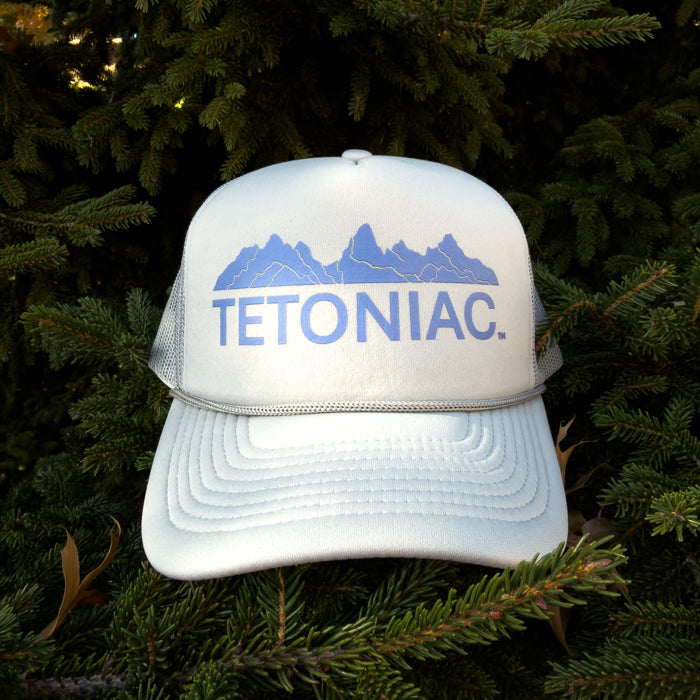 LIGHT GREY cap with 'TETONIAC' text and mountain design on a green leafy background