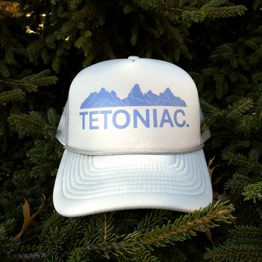LIGHT GREY cap with 'TETONIAC' text and mountain design on a green leafy background