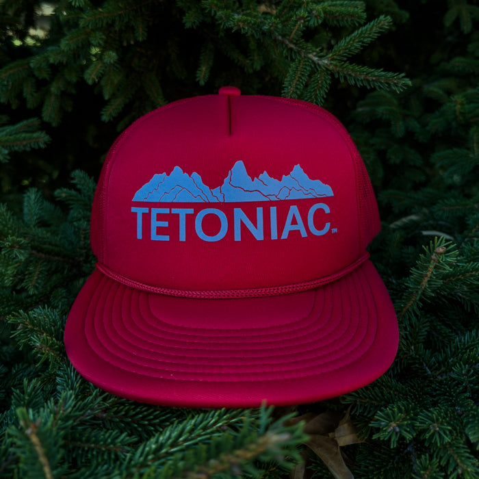 Red cap with 'TETONIAC' logo on green foliage