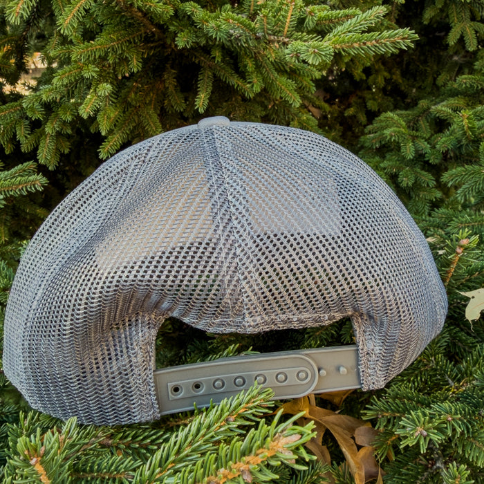Gray mesh cap on a background of green pine branches