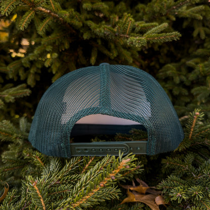 FOREST GREEN  mesh cap on a bed of pine needles