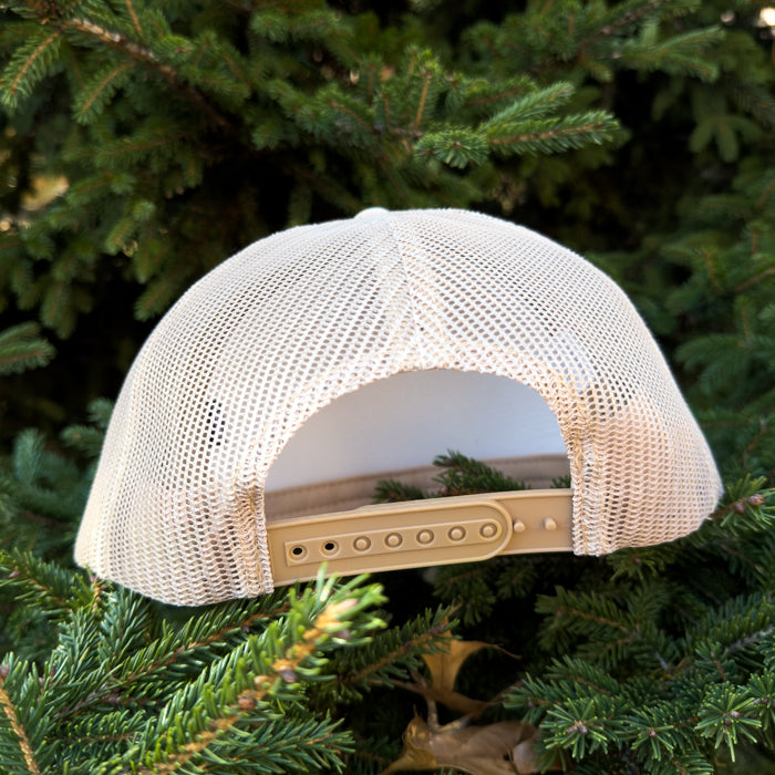 Beige mesh cap with beige bill on a green pine branch background